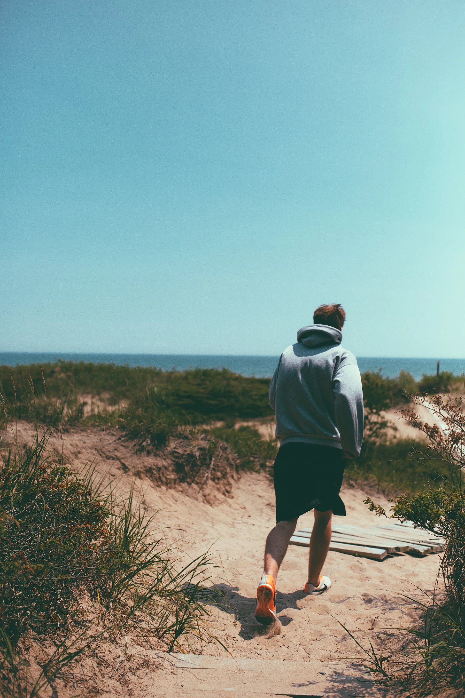 Homme qui marche sur un sentier de sable vers la mer