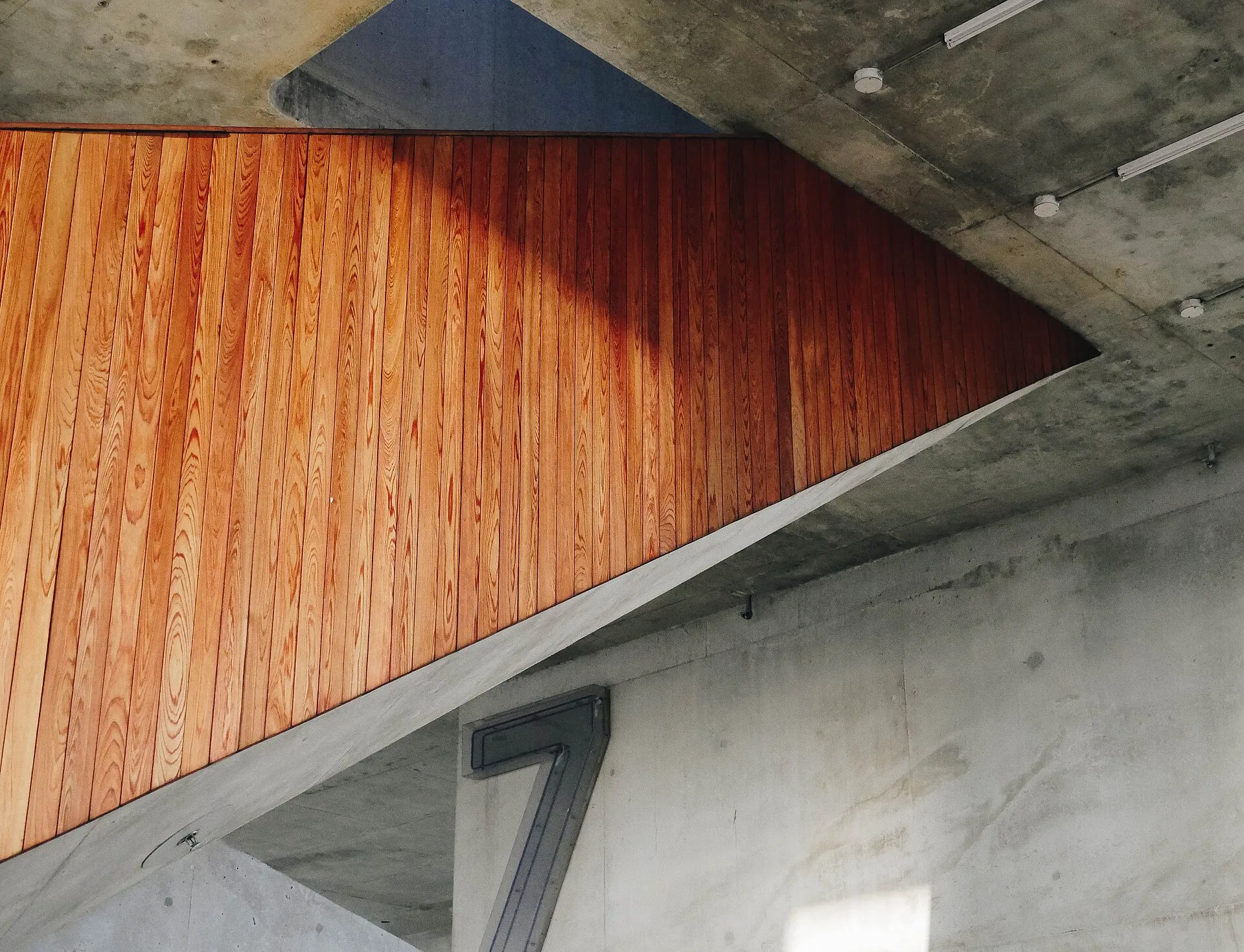 Habillage en lames de bois sous une volée d'escalier en béton